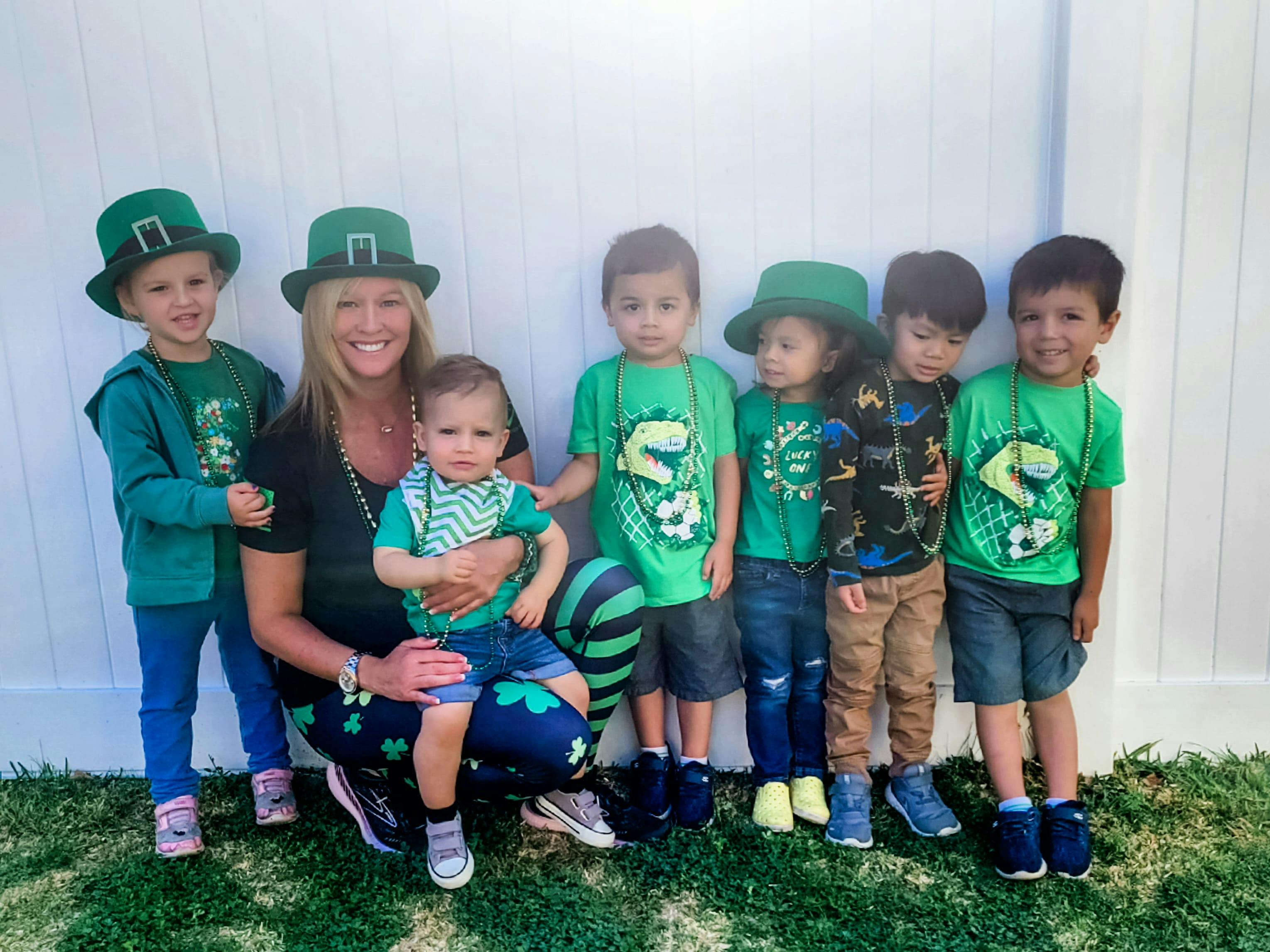 Person and multiple children wearing green clothing and hats