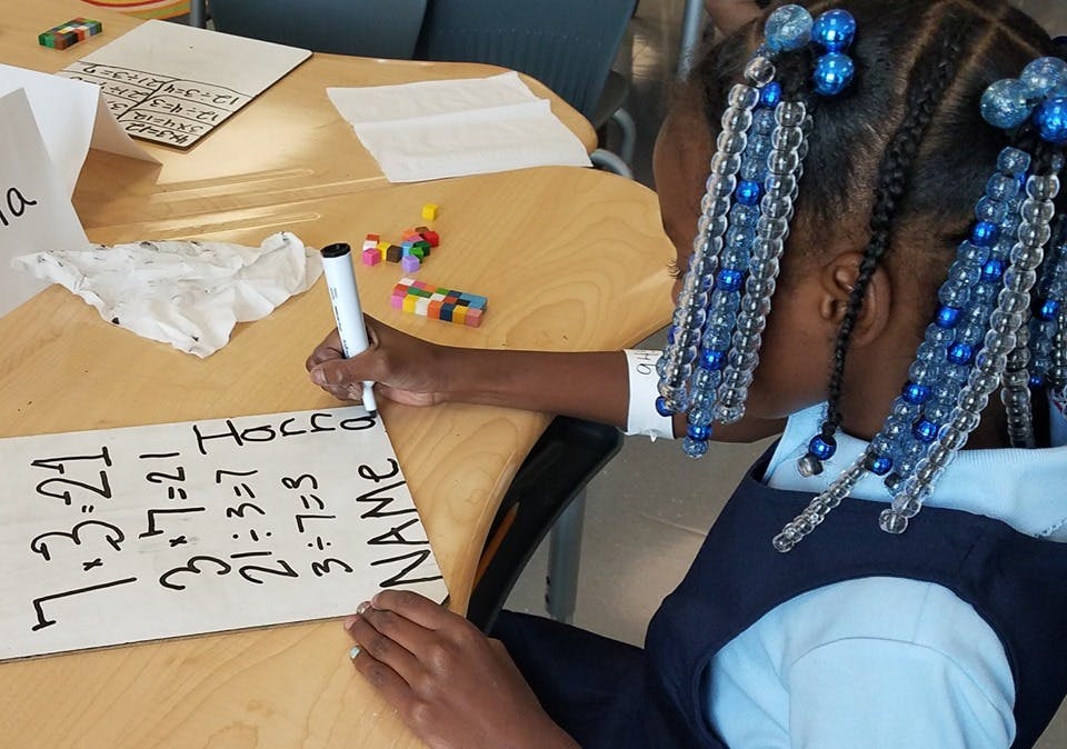 Child writing on a whiteboard with math problems