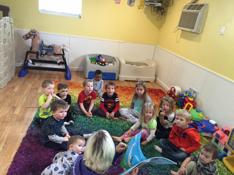 Adult reading to a group of children in a classroom