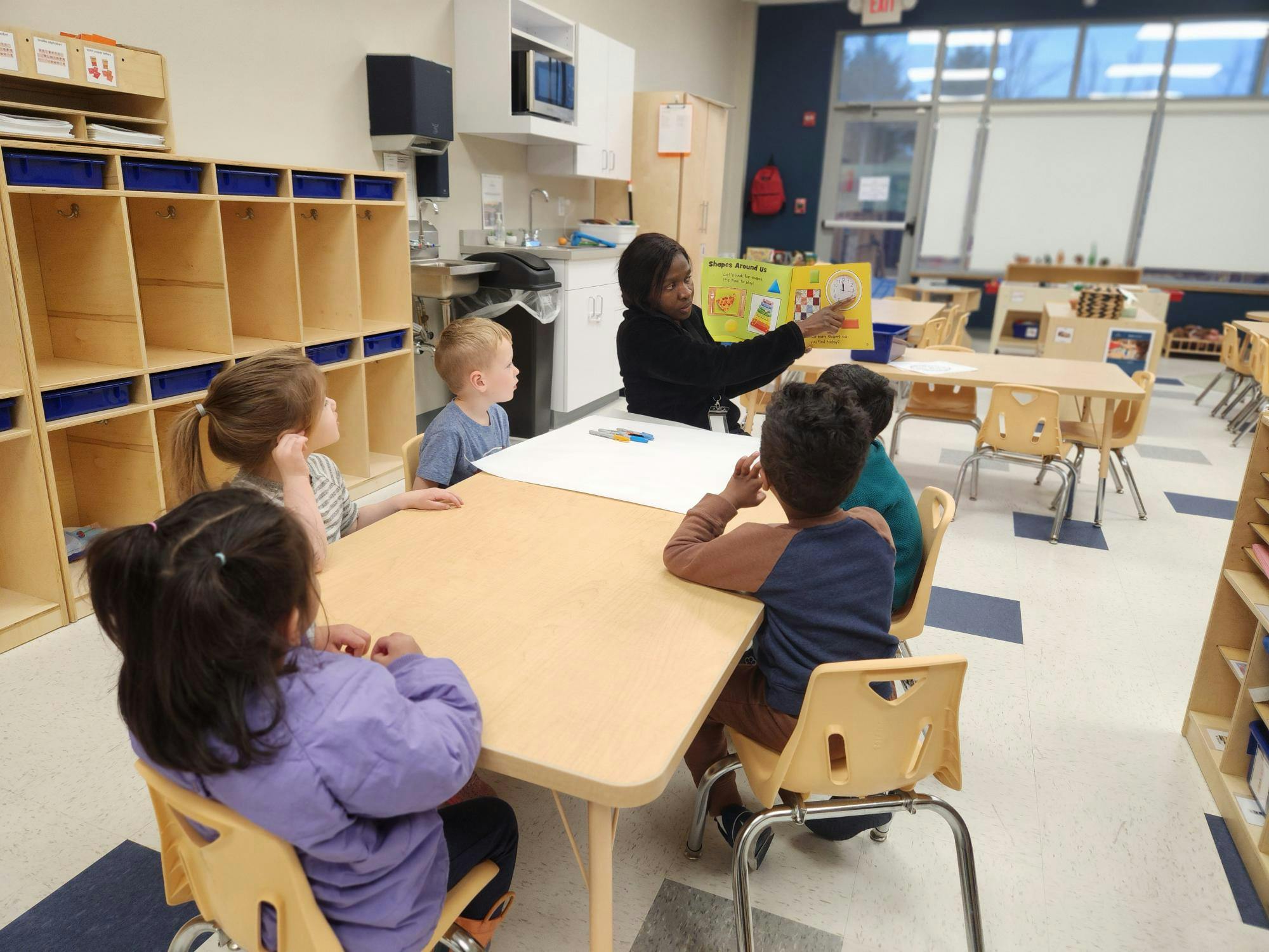 Person reading a book to children in a classroom