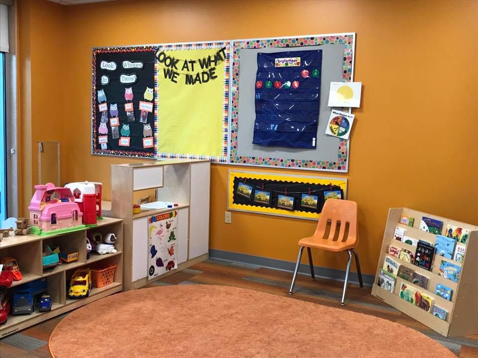 Classroom with bulletin boards, toys, and a small orange chair