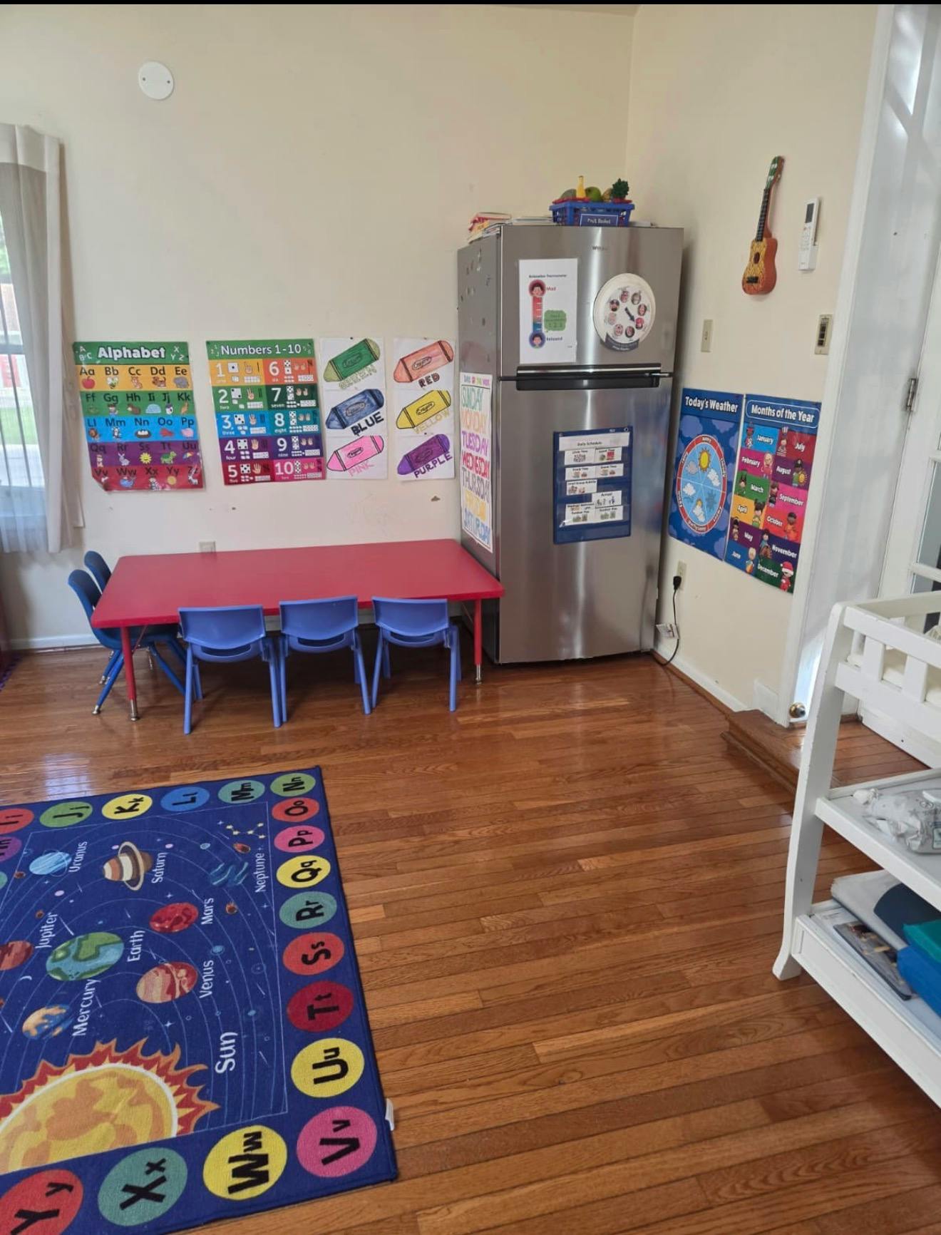 Classroom interior with small red table and blue chairs on a solar system rug