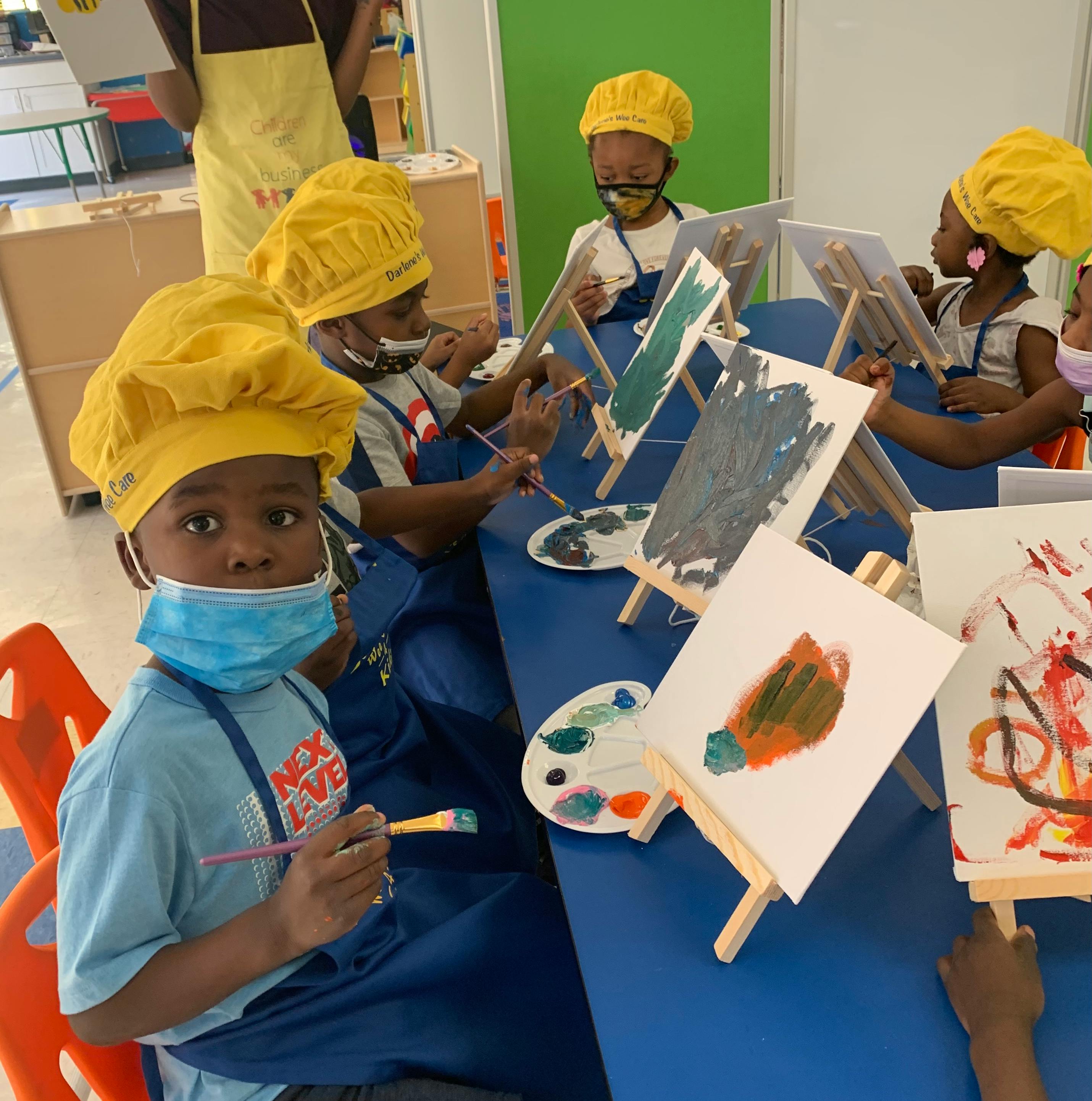 Children painting on canvases in a classroom