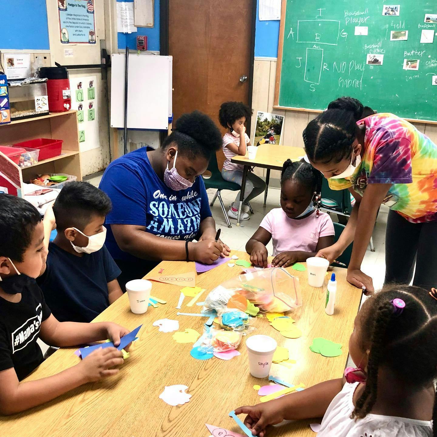 People and children crafting at a table in a classroom