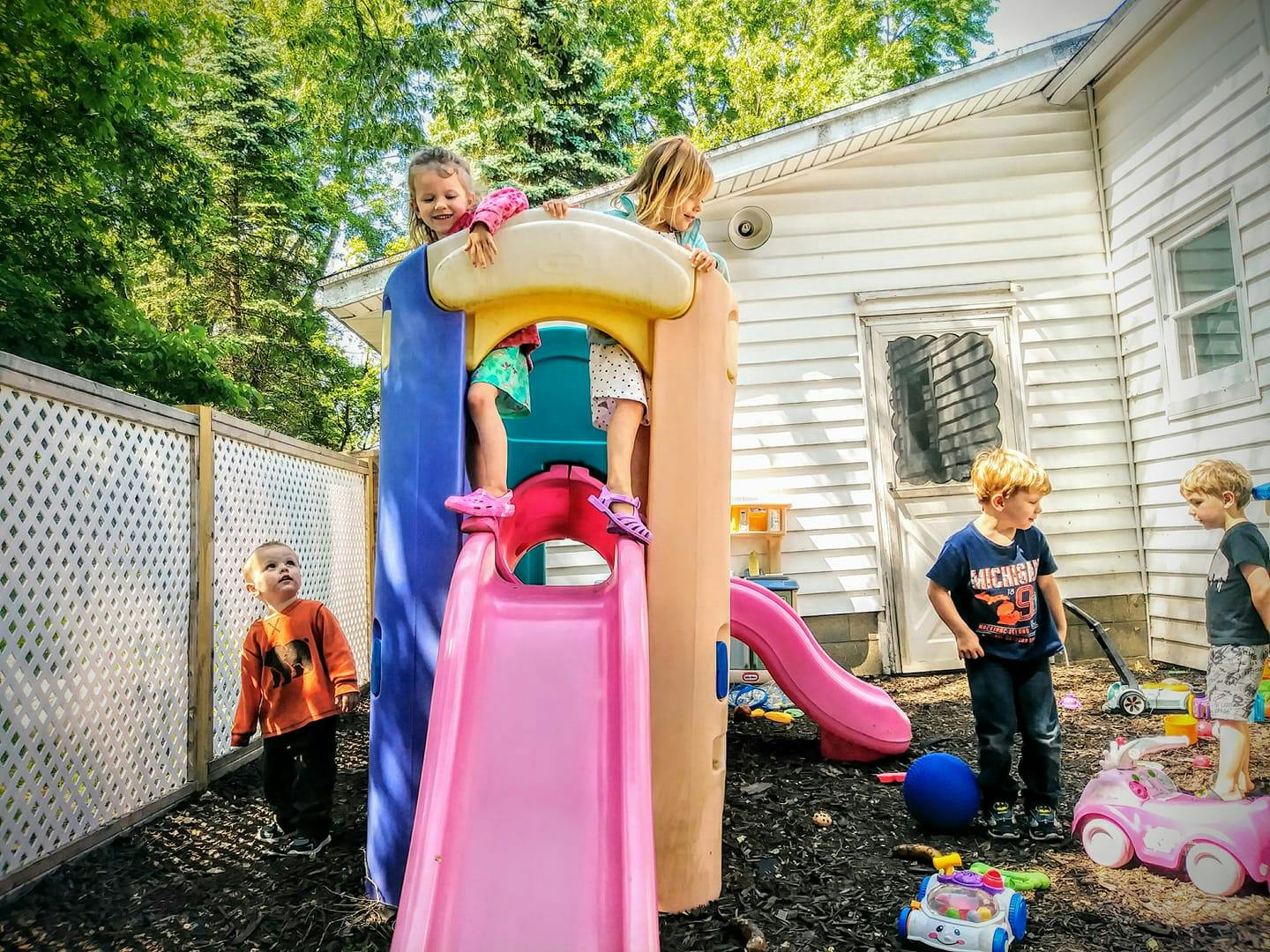 Children playing on a slide and playground structure outdoors