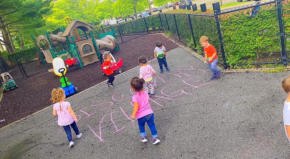 Children playing on a playground with chalk drawings on the ground