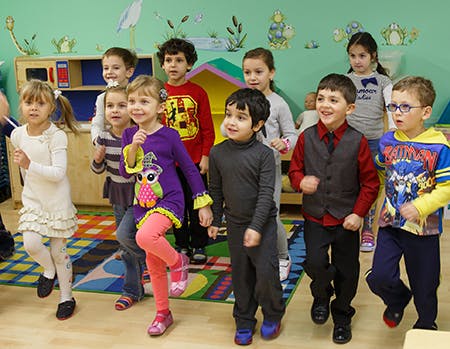 Group of children standing and moving in a classroom