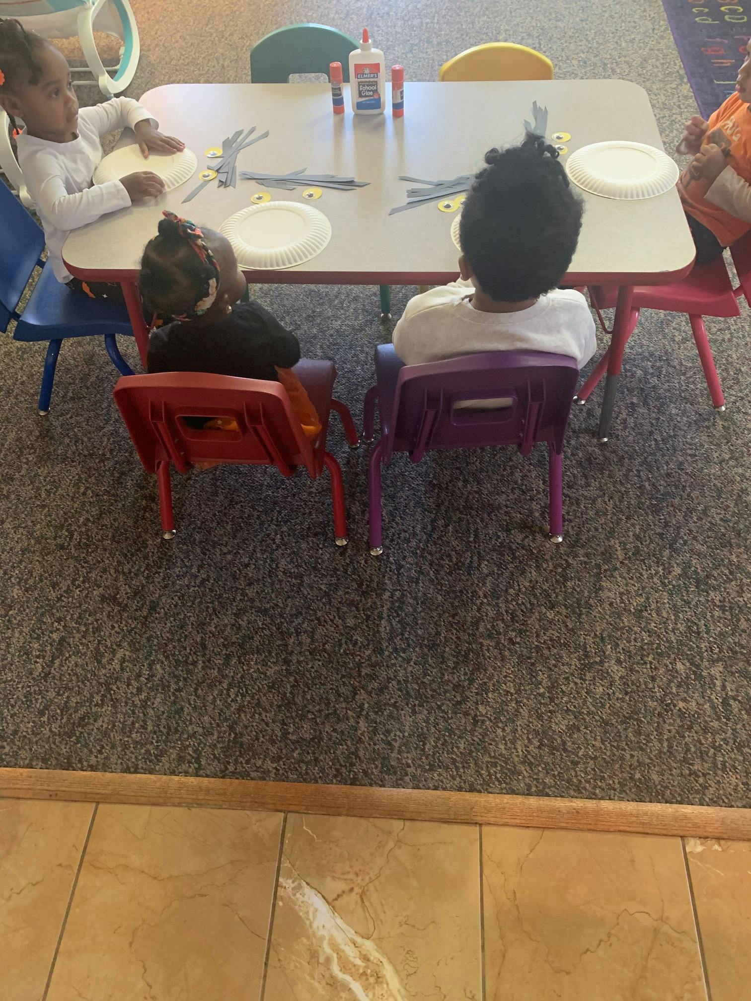 Children sitting at a table with craft supplies