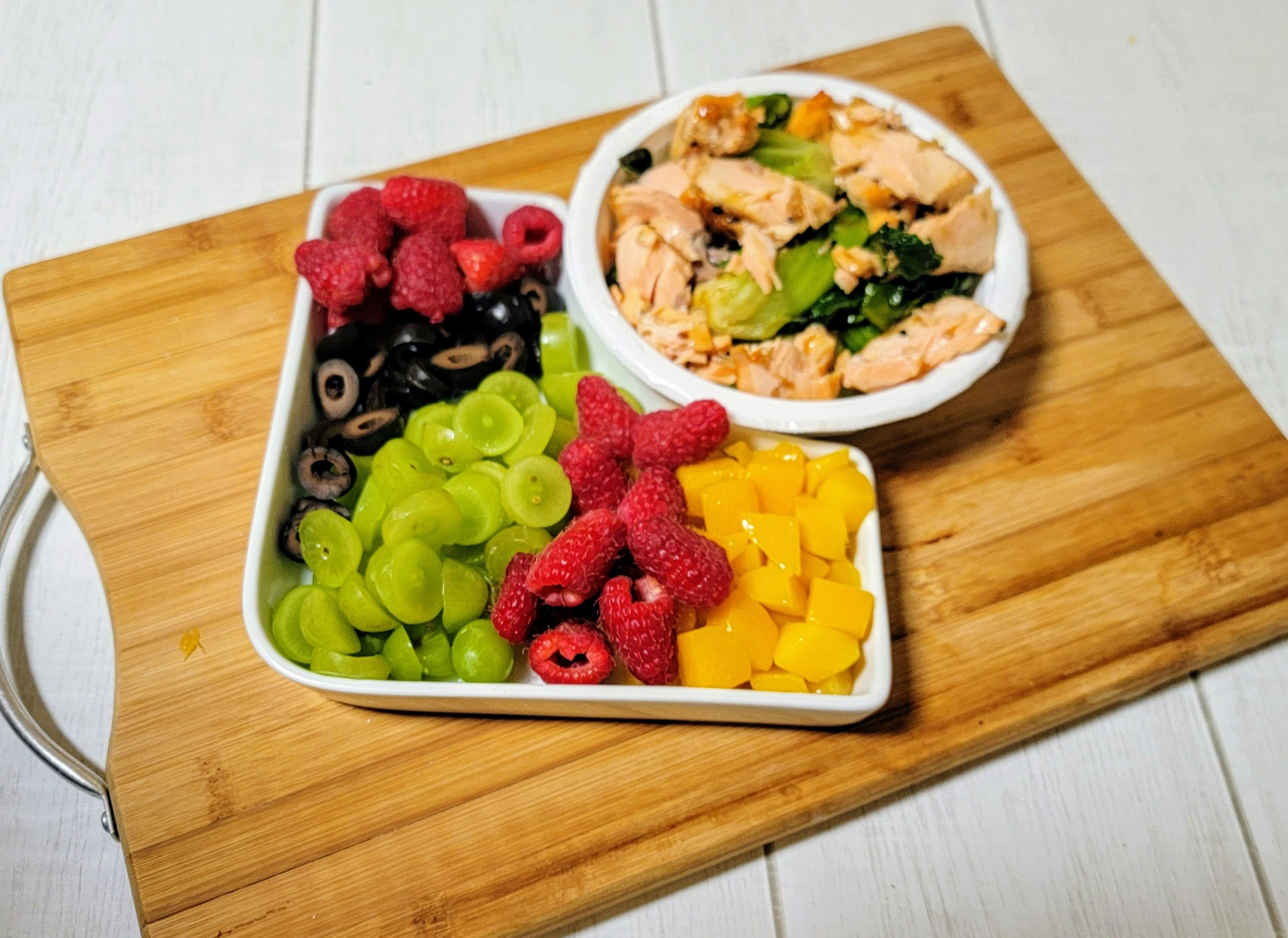 Meal with salmon and vegetables, grapes, raspberries, olives, and mango