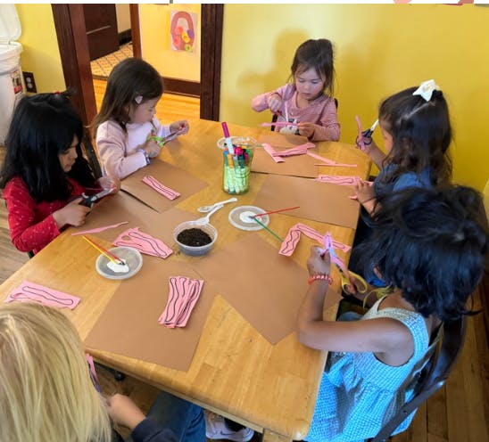 Children at a table doing crafts with paper and scissors