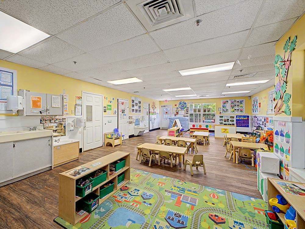 Classroom with small tables and chairs, toys, and a sink