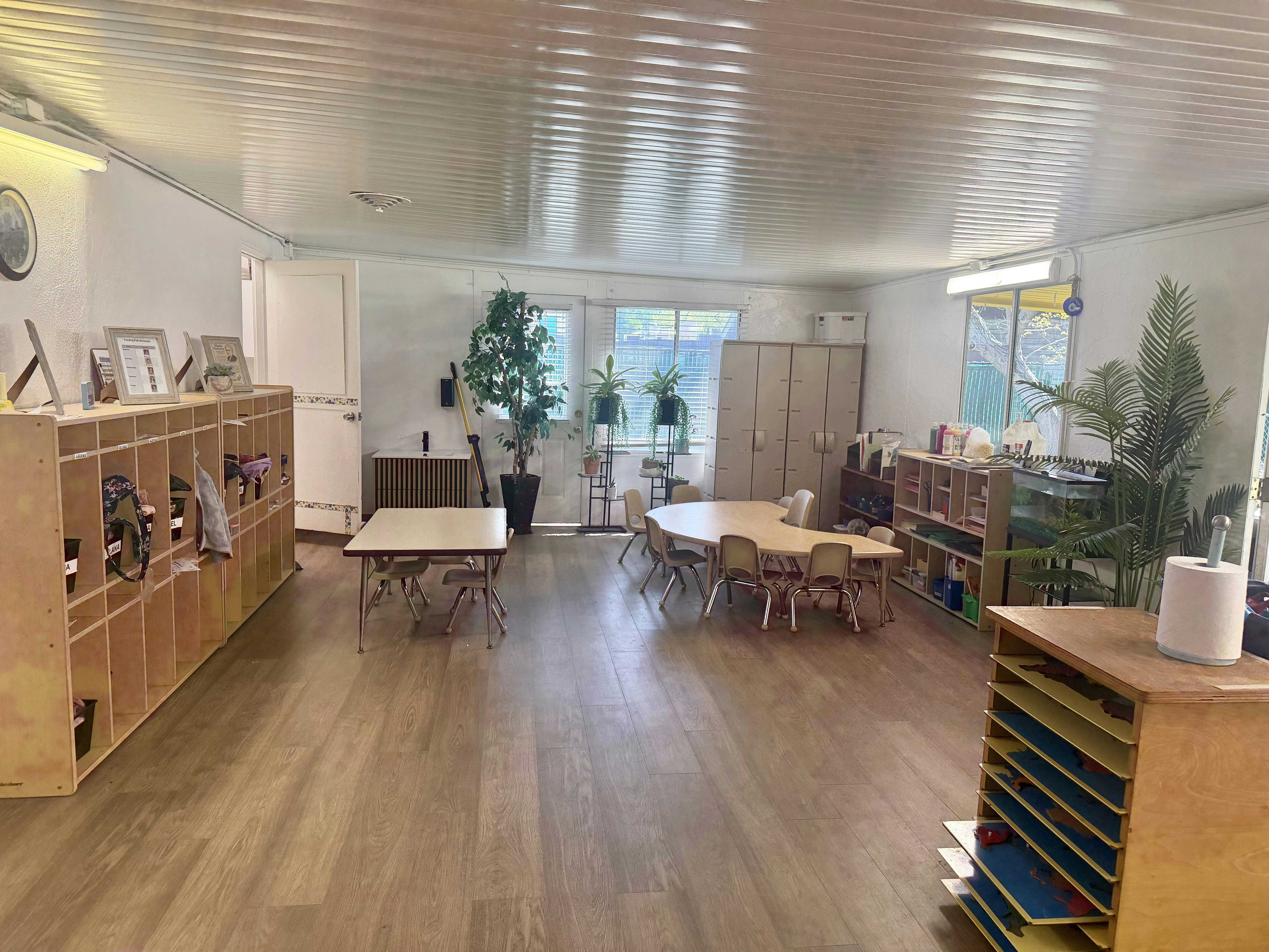 Classroom interior with small tables, chairs, and wooden cubbies