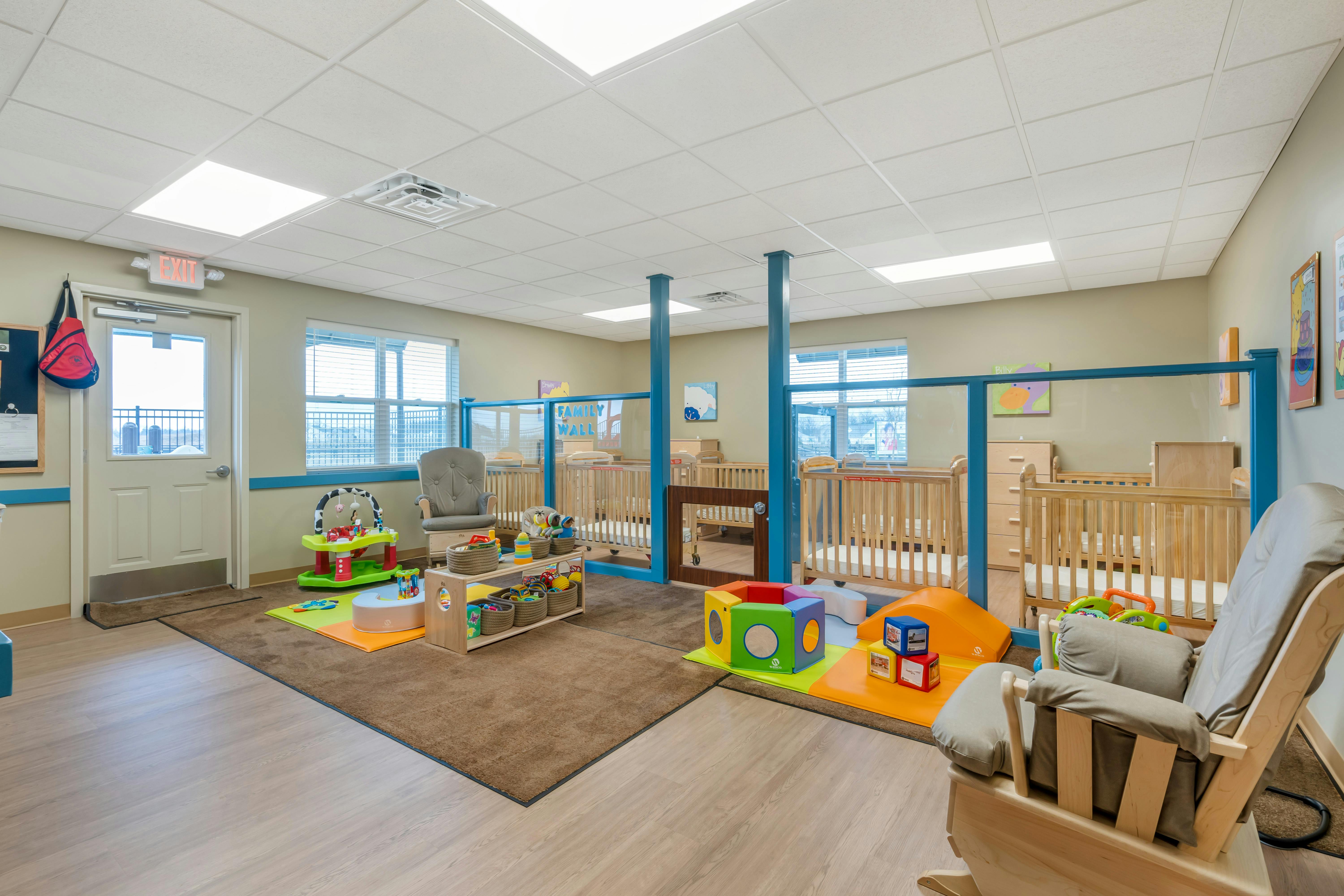 A classroom with cribs, playmats, chairs, and other children's items