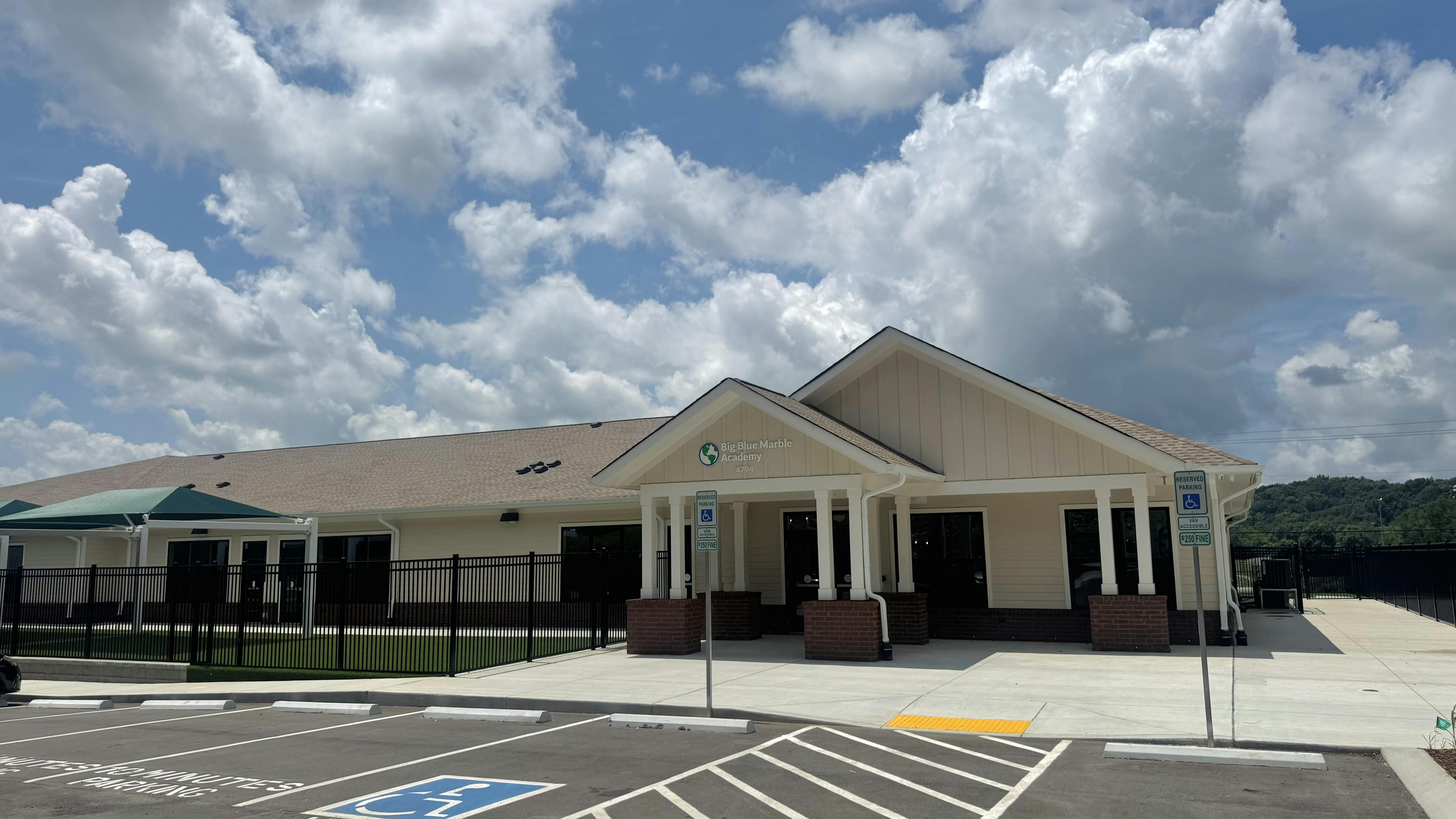 Exterior of the Big Blue Marble Academy building with a parking lot in front