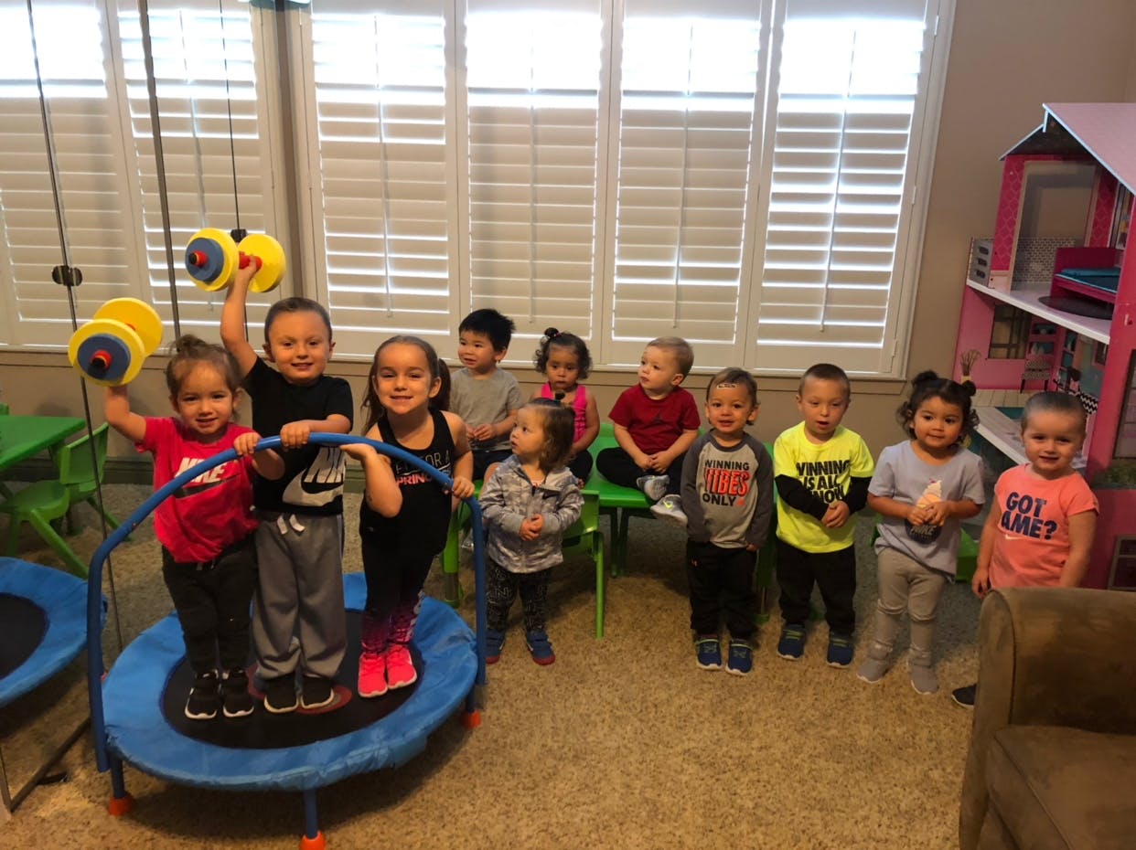 Group of children standing and playing on and around a small trampoline