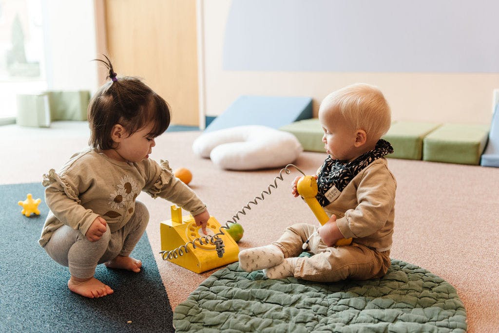 Two children playing with a toy telephone