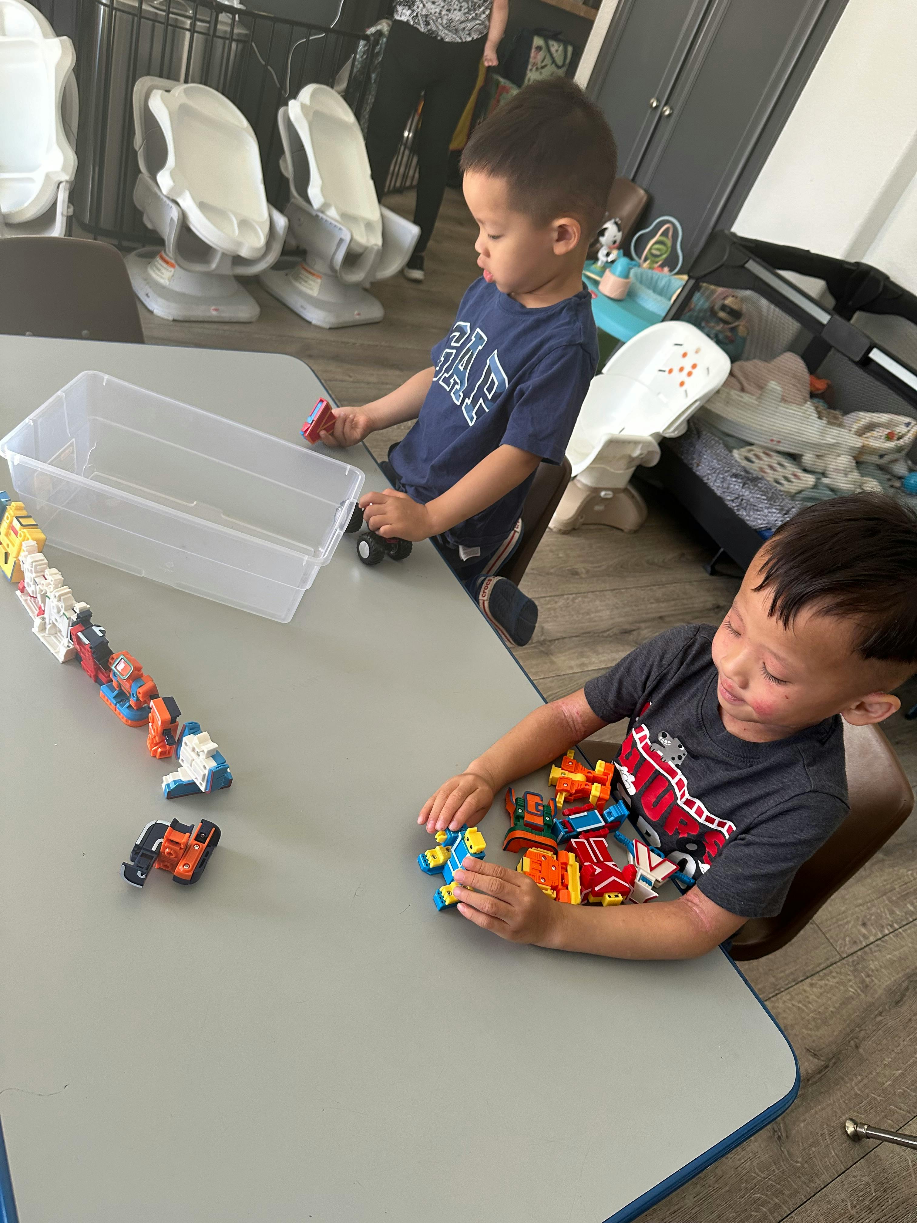 Two children playing with toy cars at a table