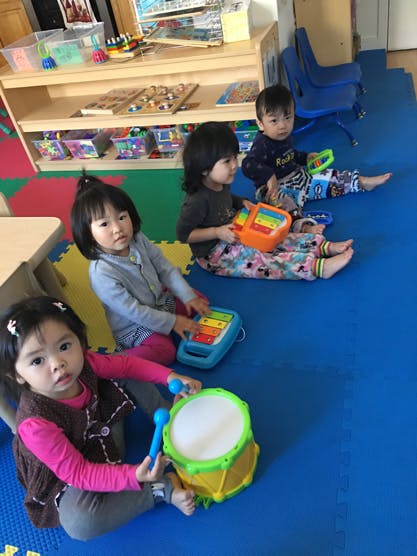 Four children playing with musical toys on a colorful mat