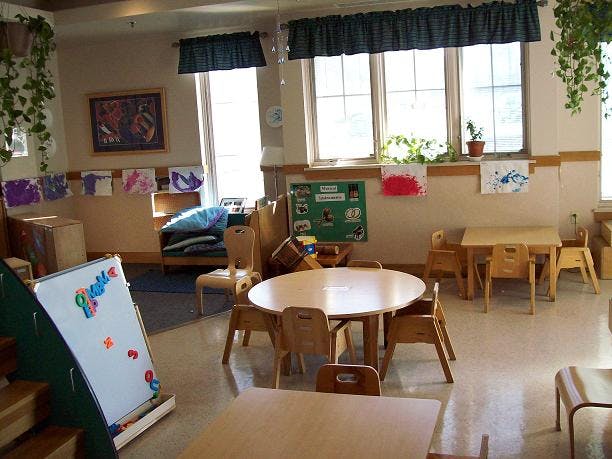Classroom with small tables and chairs, whiteboard, and windows
