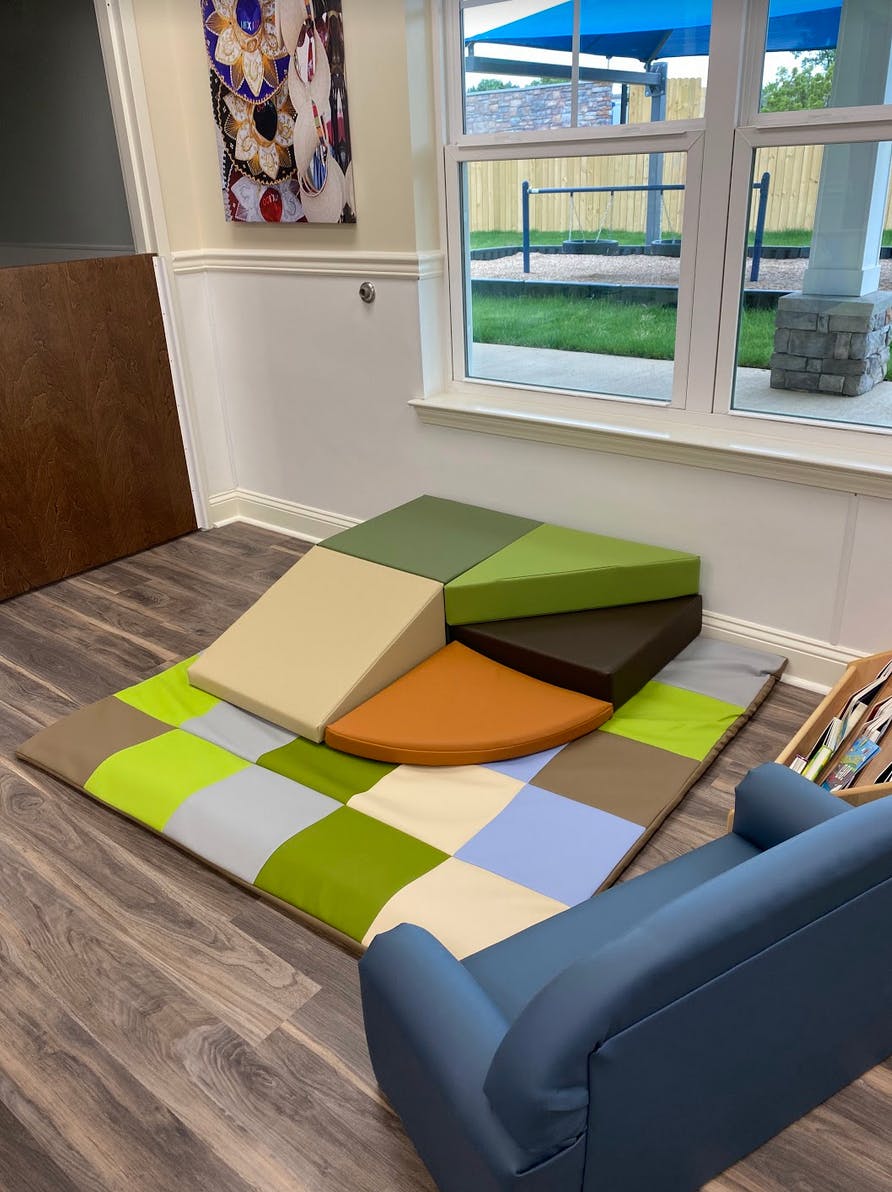 Soft play climbing blocks on a checkered mat in a room with a window