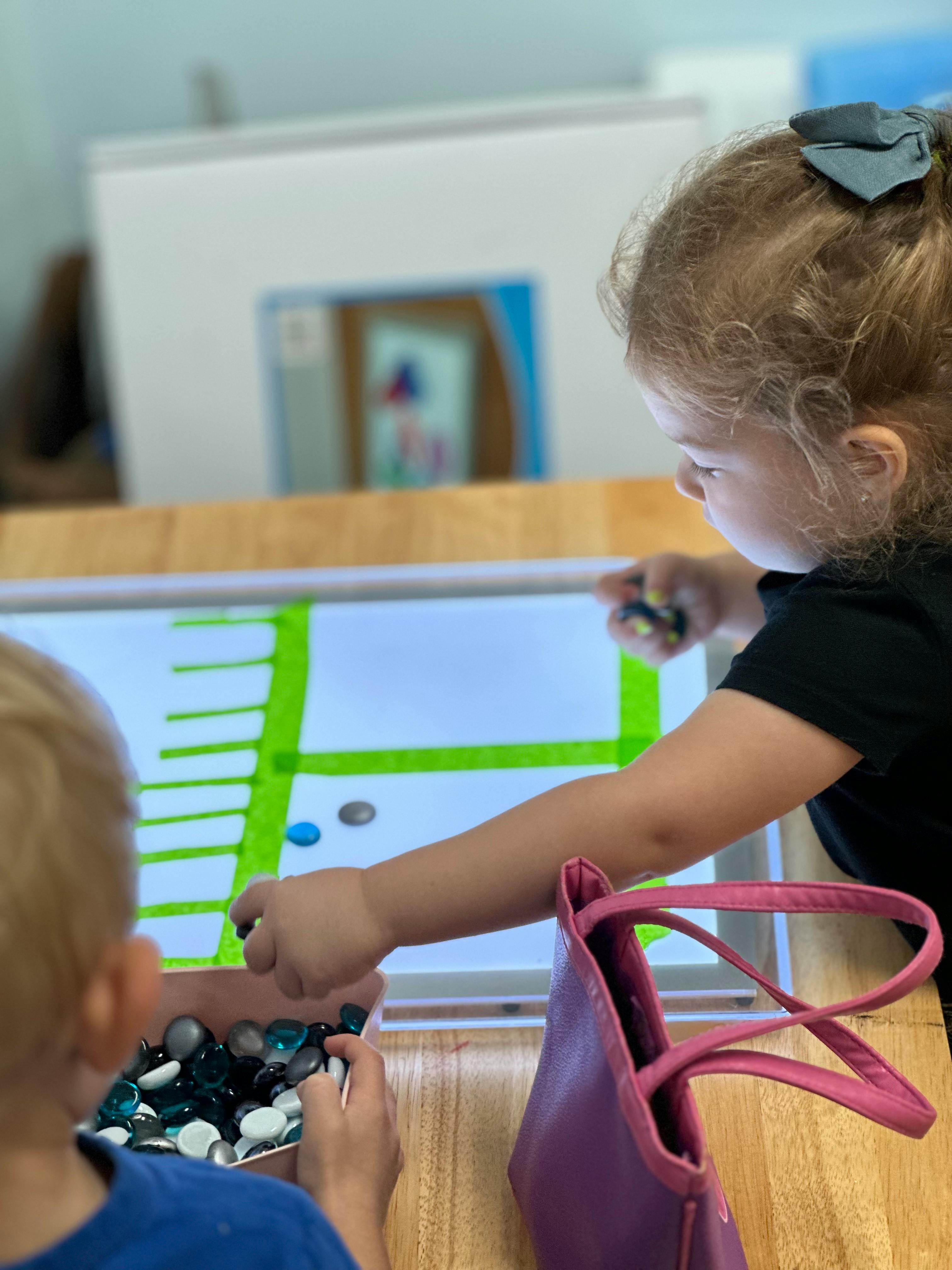 Child playing with glass beads on a light table