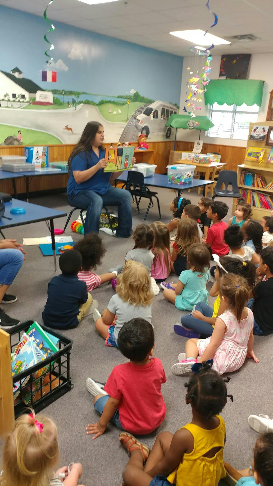 Person reading a book to a group of children in a classroom