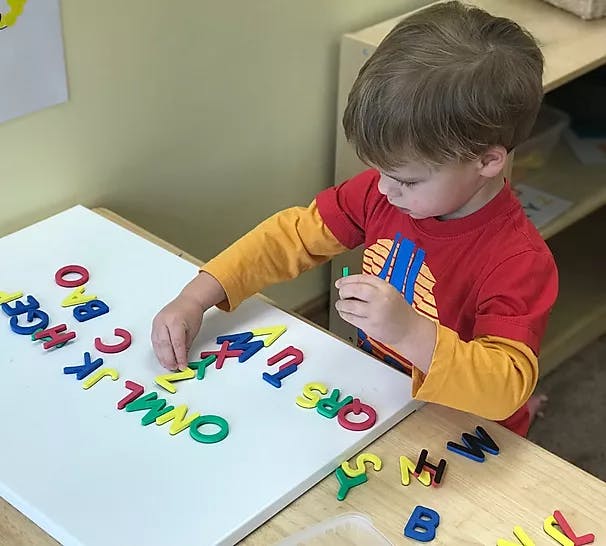Child playing with alphabet letters on a white board