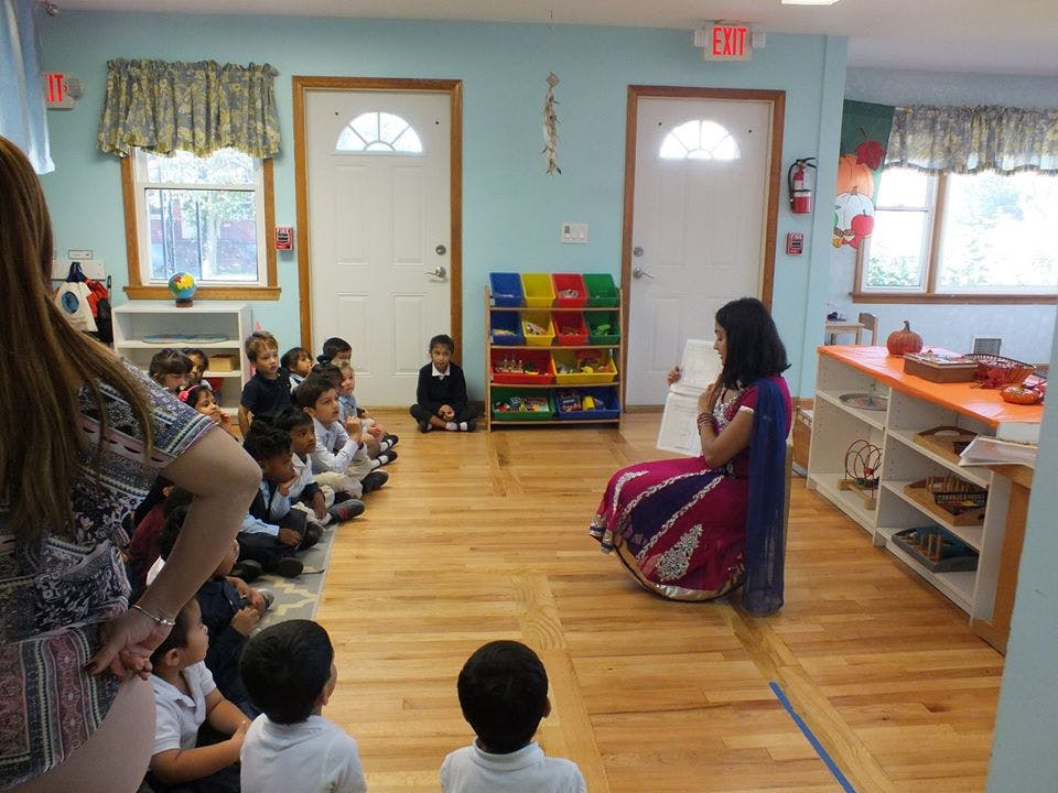 Adult speaking to children sitting on the floor in a classroom