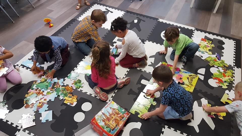 Children playing with puzzles on a mat
