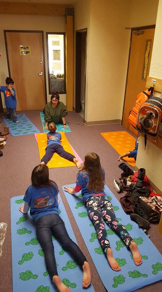 Adult and children doing yoga poses on mats