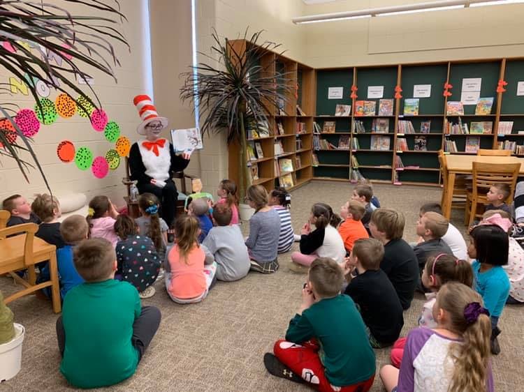 Person in Cat in the Hat costume reading to children in a library