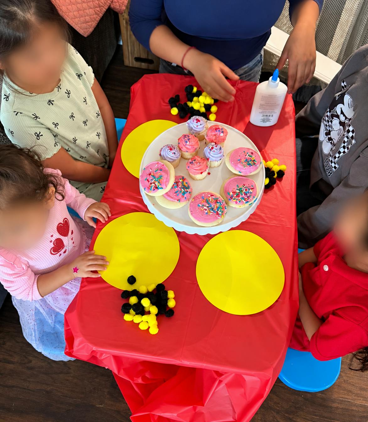 People seated around a table with cupcakes and craft supplies
