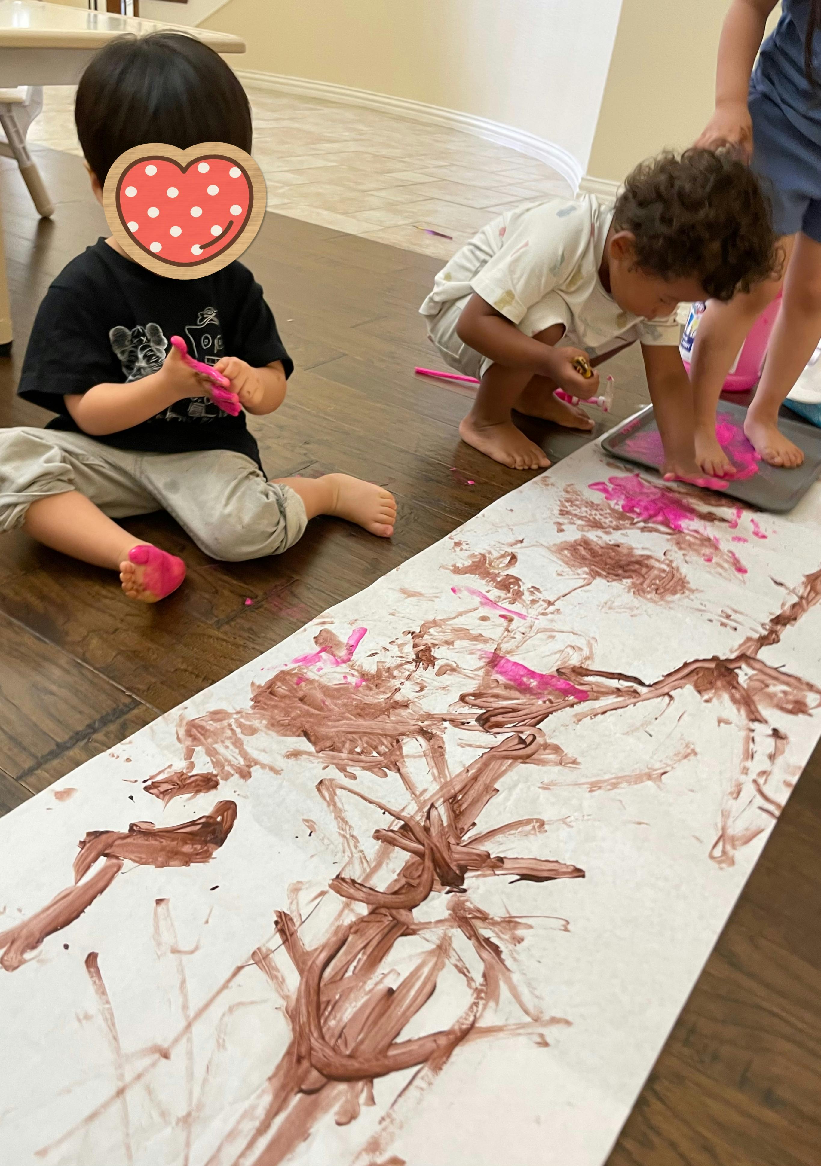 Children finger painting on a long sheet of paper on the floor
