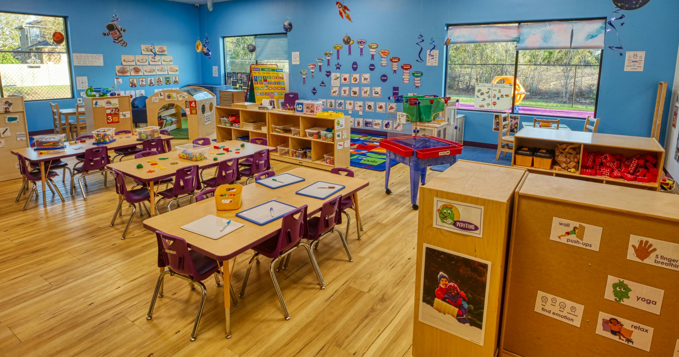 Empty colorful classroom with tables, chairs, and learning materials