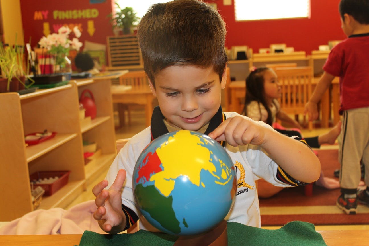 Child pointing at a globe in a classroom