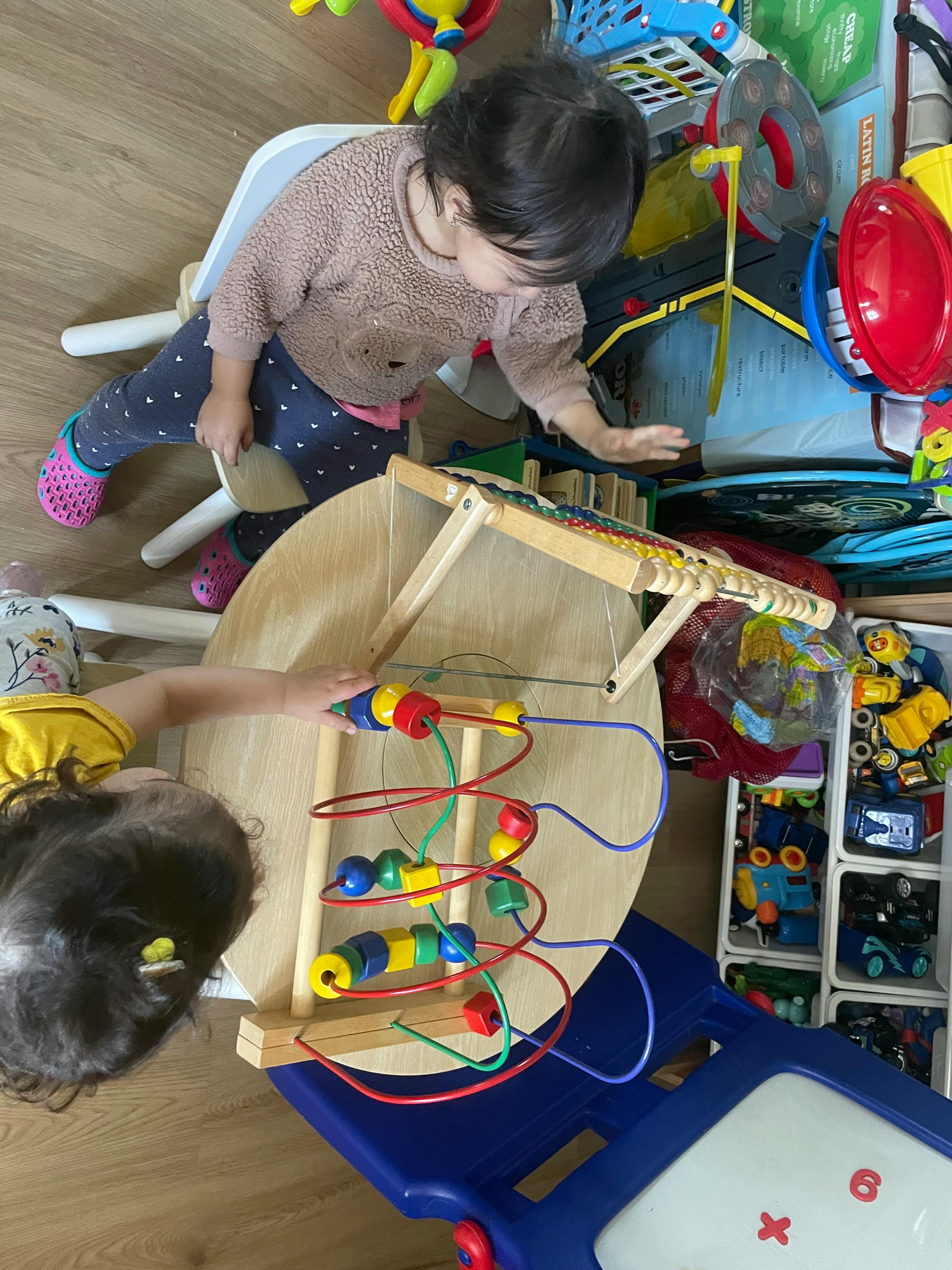Two children playing with a bead maze toy