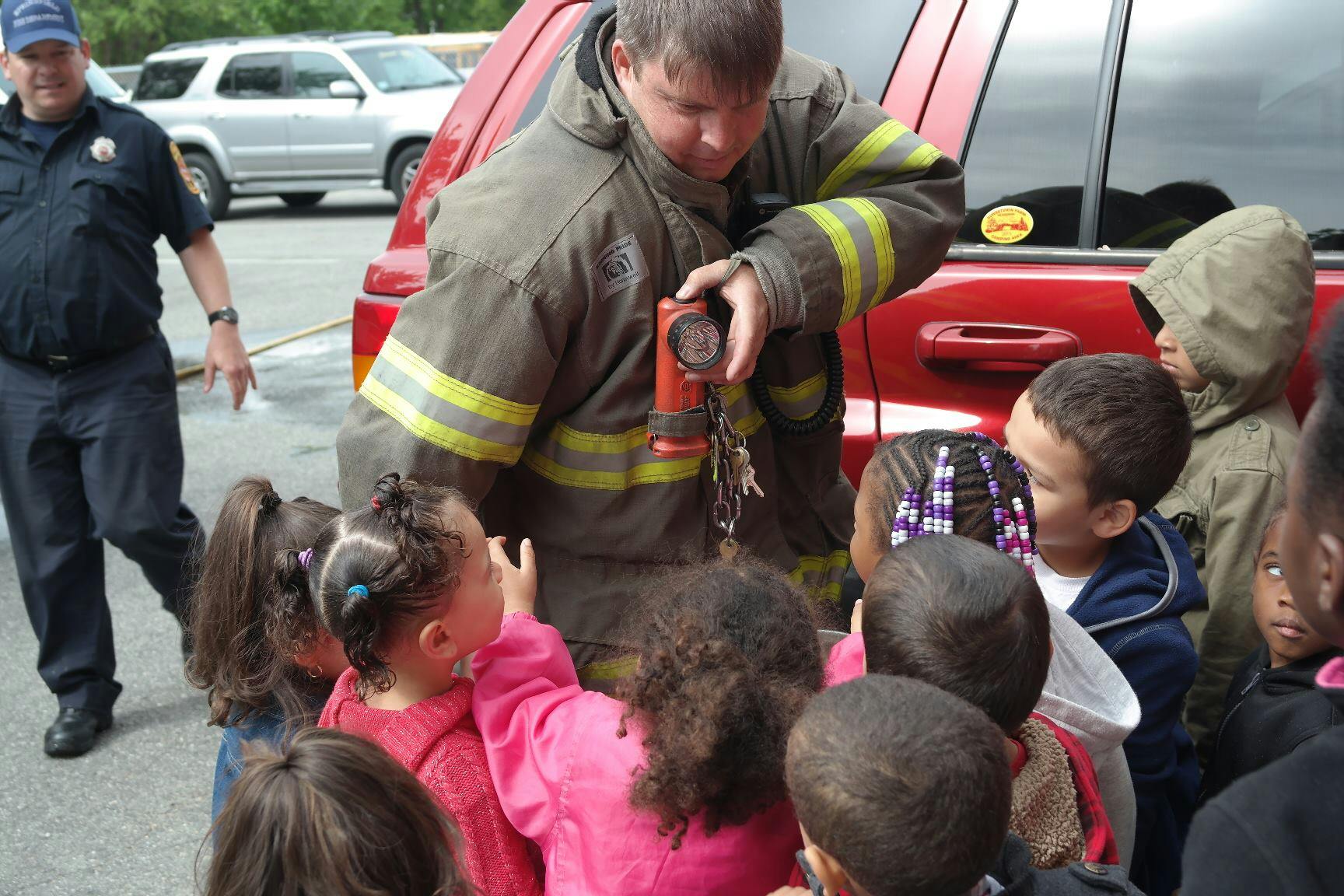 Firefighter showing equipment to a group of children