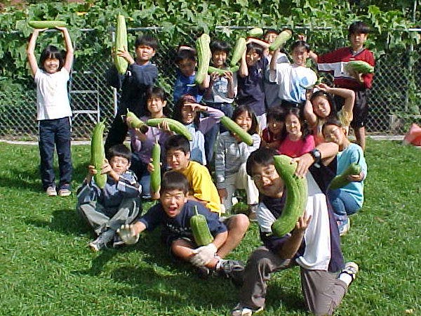 Group of children and adults holding large green gourds outdoors