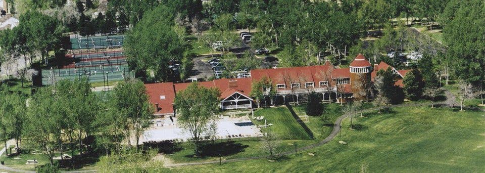 Aerial view of a building with a red roof and tennis courts