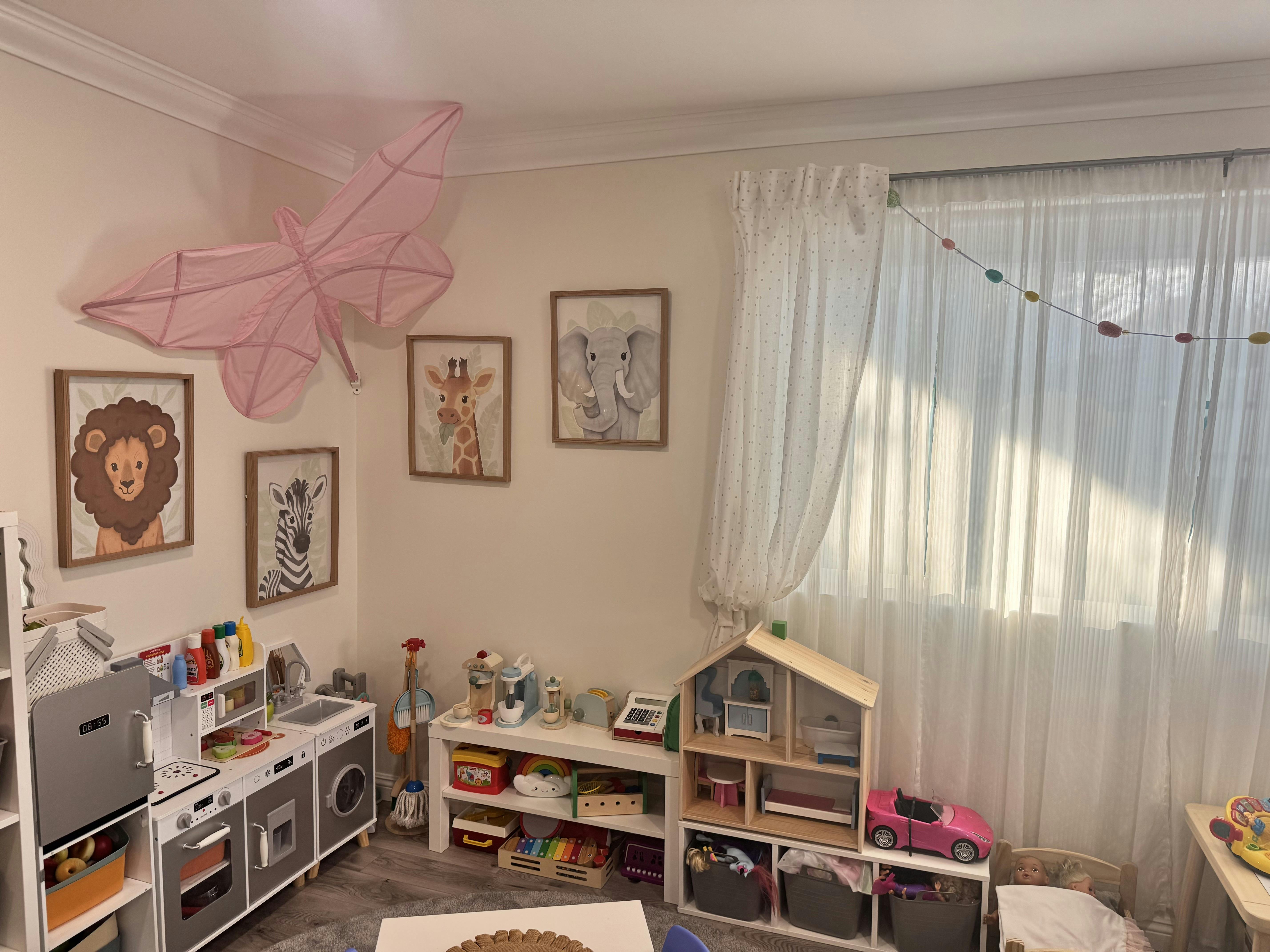 Playroom with toy kitchen, dollhouse, and animal pictures on the wall