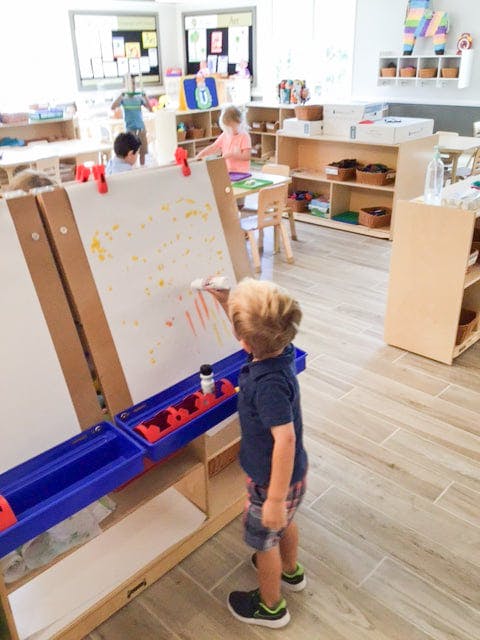 Child painting at an easel in a classroom
