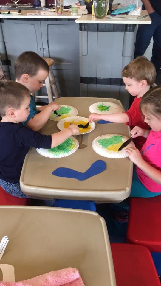Children painting on paper plates at a table