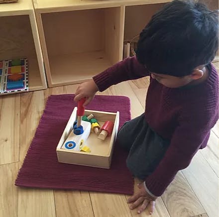 Child playing with a wooden toy hammer and pegs