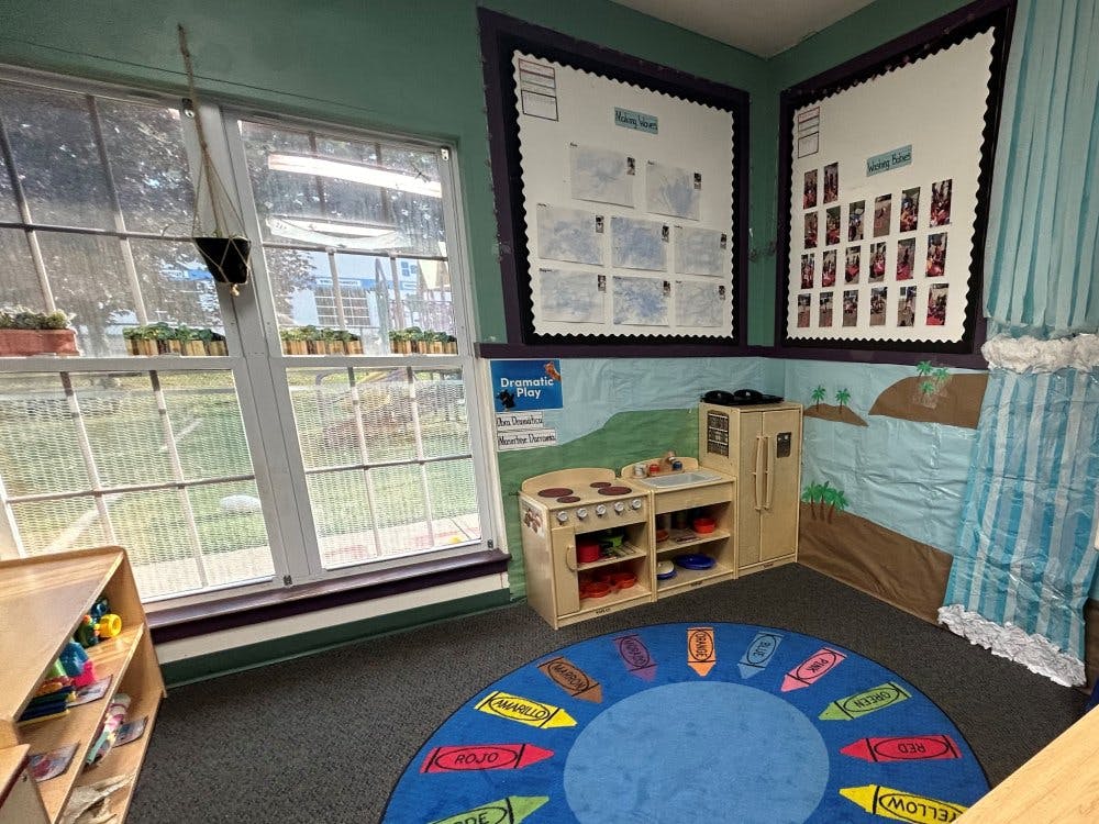 Children's play kitchen area with a crayon-themed rug in a classroom