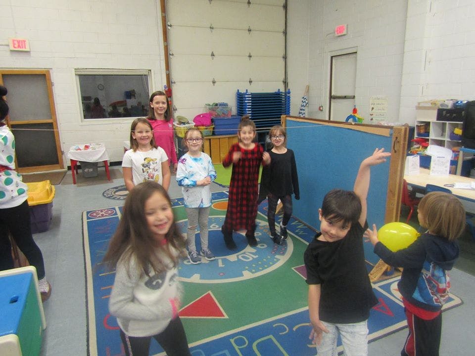 Children playing in a room with a person standing in the background