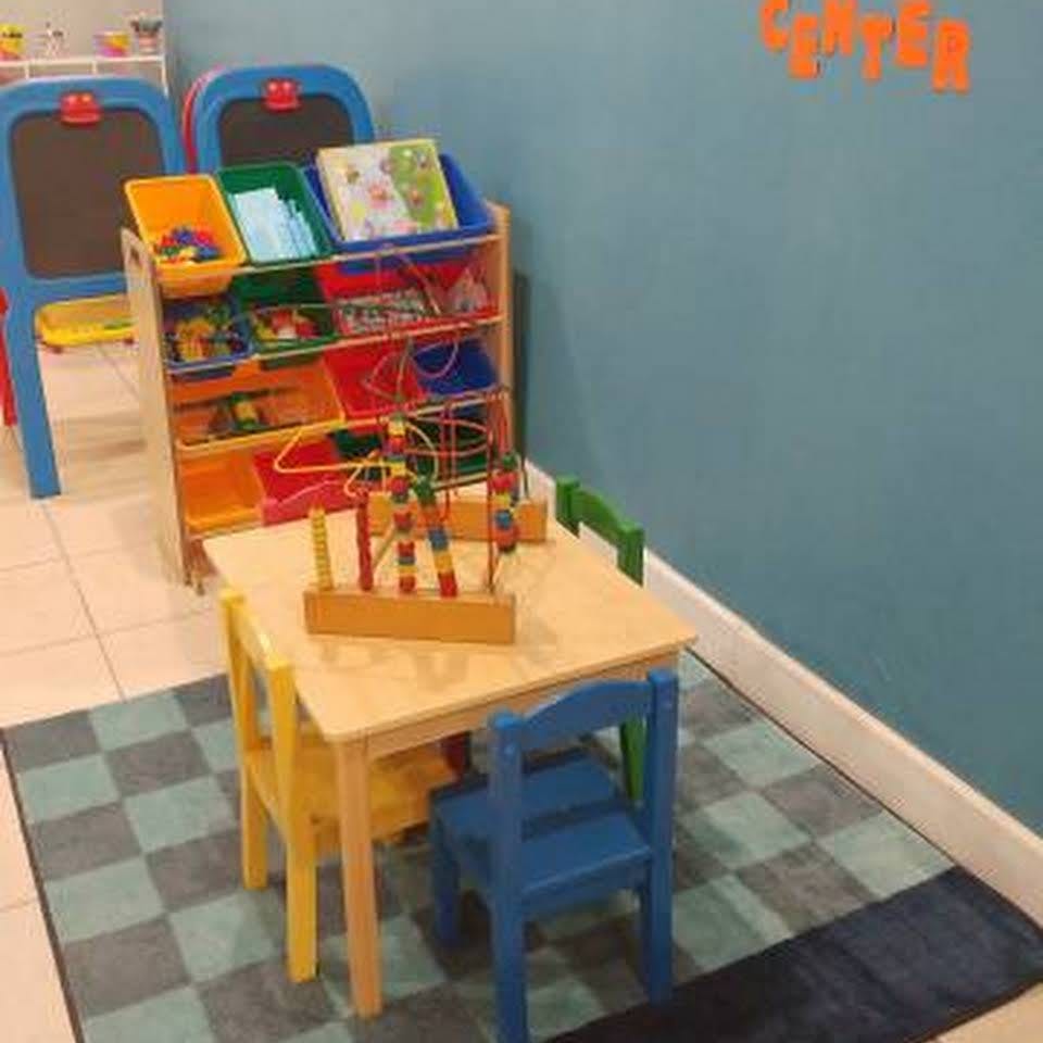 Children's play area with small table and chairs, toy organizer, and easels