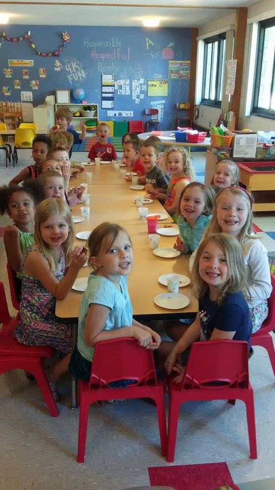 Group of children sitting at a long table in a classroom