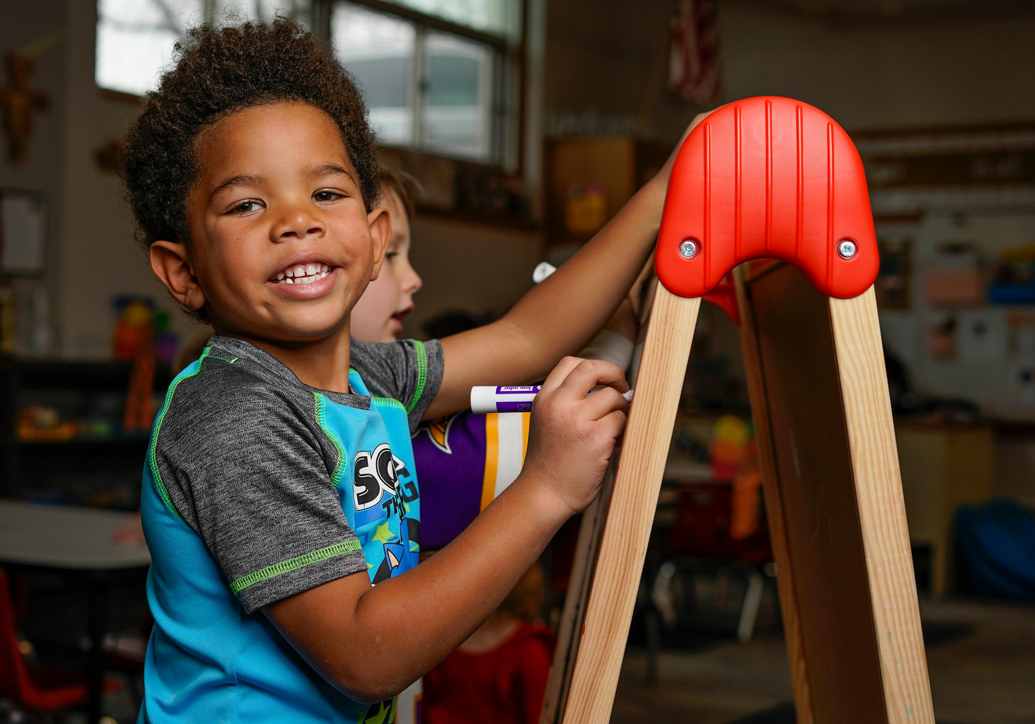 Child writing on an easel in a classroom