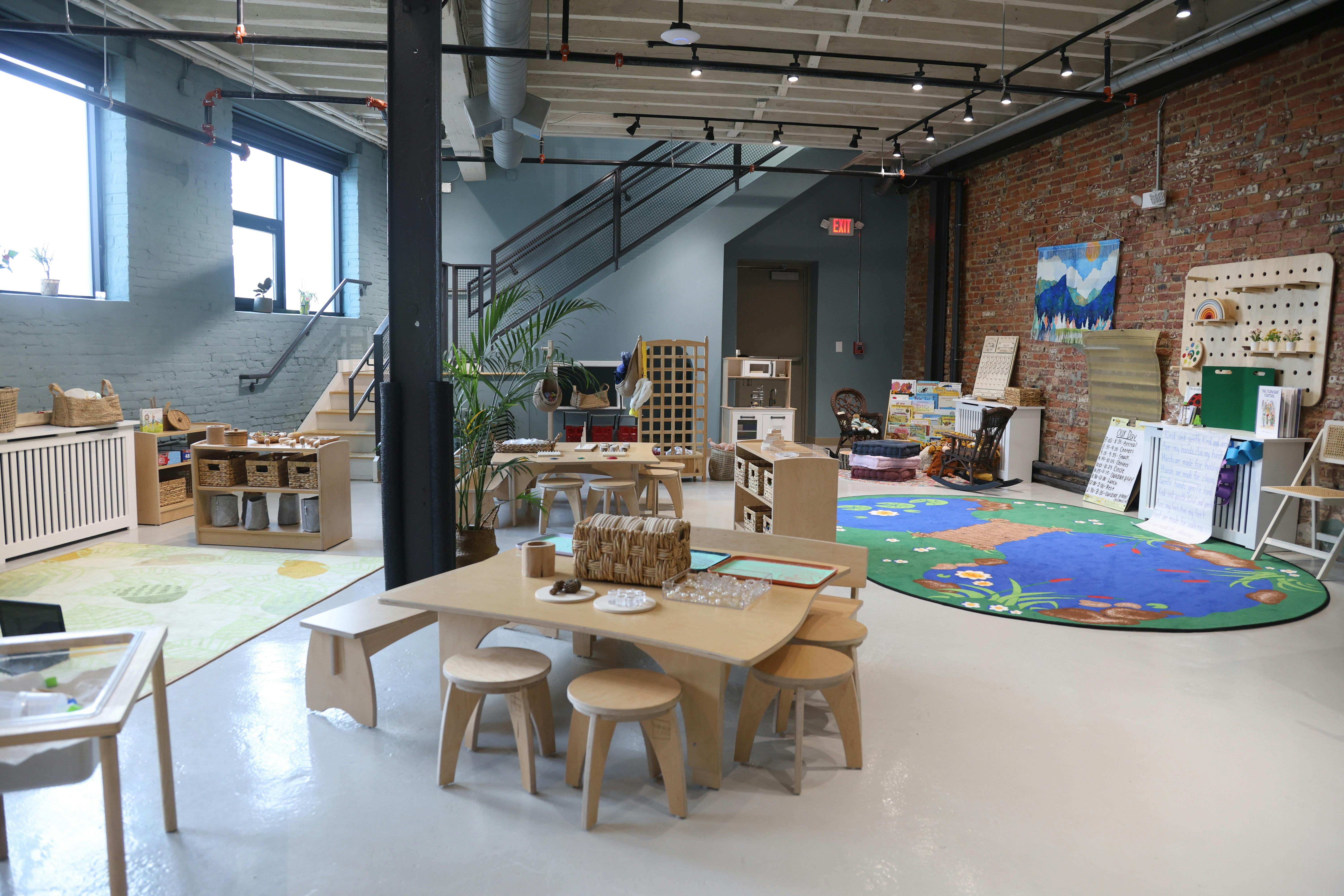 An empty classroom with small tables and chairs, toys, and a pond-themed rug