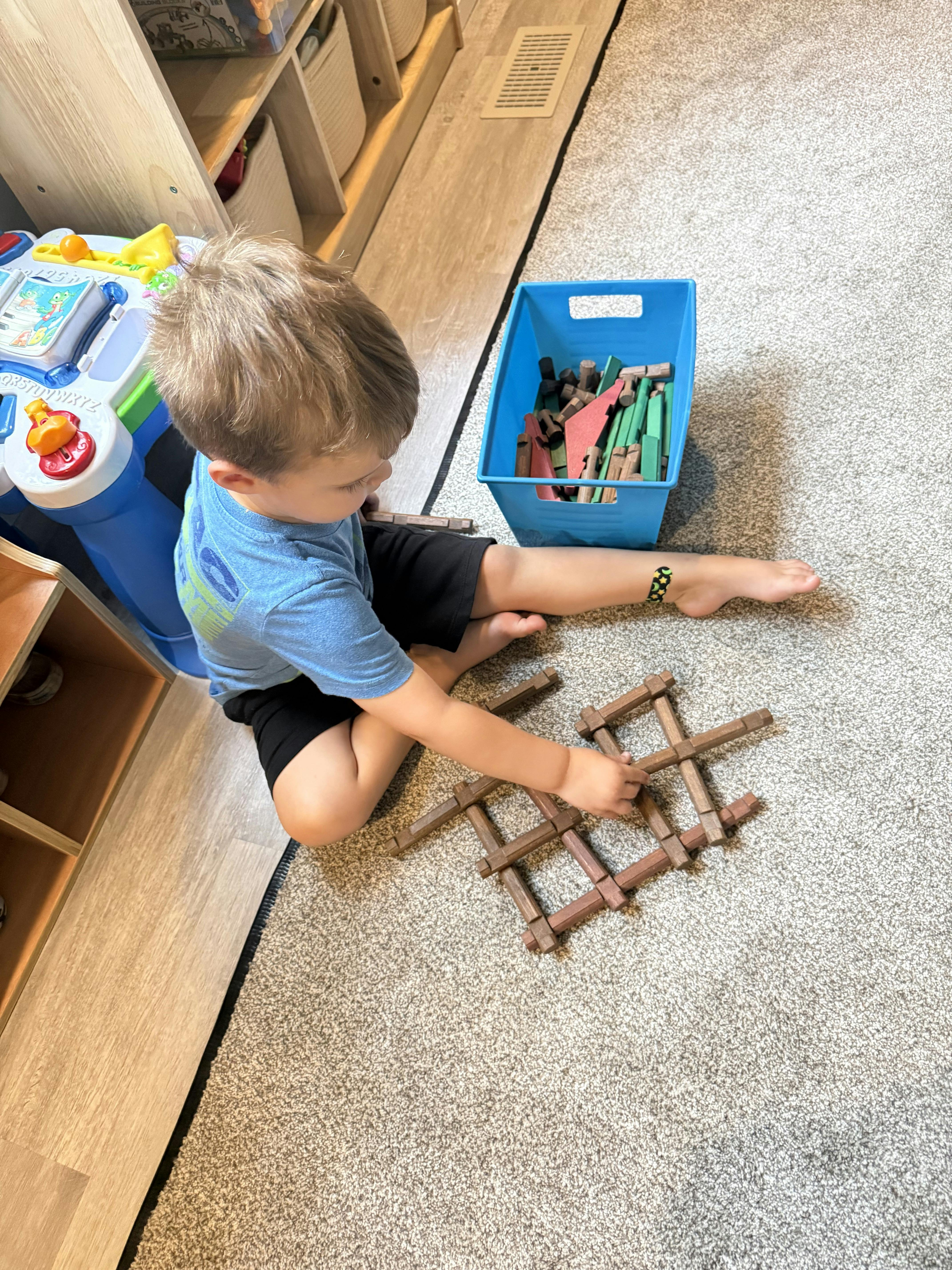 Child sitting on a carpet floor building with wooden blocks